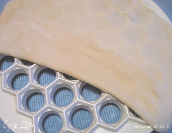 Готовое тесто разделить на несколько порций, так удобнее всего воспользоваться специальной формой для пельменей. Раскатать тесто, положить на форму.