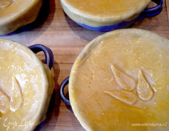 Накрываем горшочки тестом и закрепляем его по верхнему краю горшочков. Смазываем верхушки желтком. Отправляем в духовку на 10 минут.