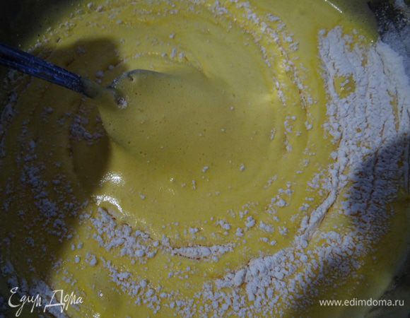 В остывшую массу аккуратно частями ввести просеянную муку.  Тесто вылить на плоский противень с бортиком, застеленный бумагой и сбрызнутый масляным спреем. Выпекать около 15 минут. Во время выпекания духовку не открывать: бисквит может  не подняться.  