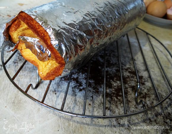 Еще горячий бисквит вместе с бумагой свернуть в рулет и переложить на решетку. Оставить охлаждаться.  