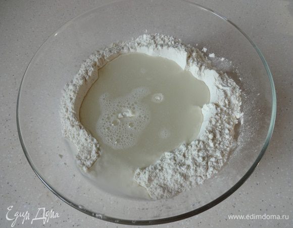 В просеянную муку добавить соль и дрожжи. Сделать углубление и добавить теплую воду.