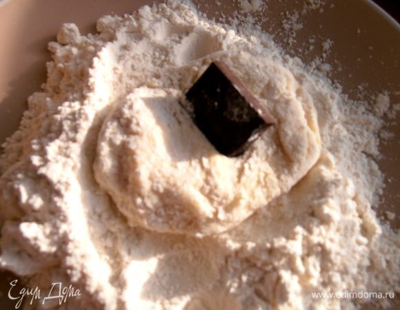 Начинаем обваливать,как обычные сырники,но останавливаемся на полпути,сплющиваем тесто и прячем в серединку кусочек Вашего любимого шоколада.Закрываем кусочек и немного ещё пообваливаем сырничек в руках с мукой.