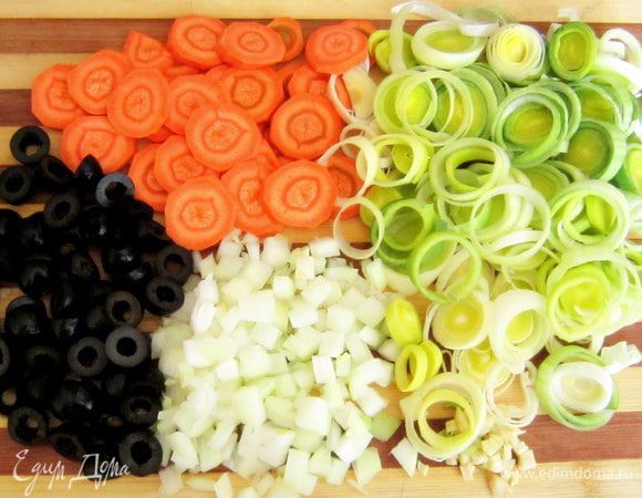 Морковь нарезать кружочками, лук порей нарезать кольцами, репчатый лук и чеснок мелко порезать, маслины порезать пополам.
