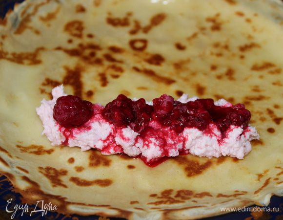 Выложить готовый блин на тарелку, смазать растопленным маслом...на край блина расположить 1-1,5 ст.л. творожной массы длинной полосой и поверх уложить ягоды малины. Малину следует предварительно разморозить при комнатной температуре, а ее сок можно добавить к творождной массе