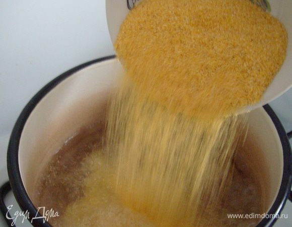 Влить в сотейник или  кастрюлю с толстыми стенками воду, после закипания воды добавить кукурузную крупу.