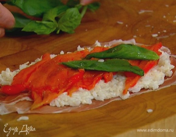 На рабочую поверхность выложить ветчину, на каждый кусочек поместить немного рисовой начинки, сверху выложить полоски сладкого перца и листья базилика. 