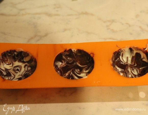 Теперь делаем мраморные конфеты. Белый и темный шоколад по очереди наносим на стенки формы. Теперь формы нужно слегка наклонять и крутить, чтобы шоколад немного перемешался и равномерно распределился по стенкам. Можно перемешать при помощи деревянной шпажки. Охладить 10 минут в морозильной камере.