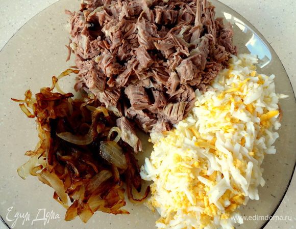 Лук нарезать тонкими полукольцами и обжарить в растительном масле до золотистого цвета. Мясо нарезать небольшими кусочками, вареные яйца натереть на тёрке.