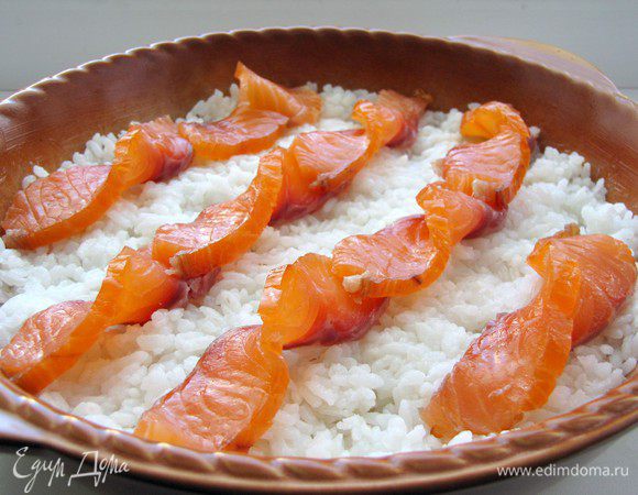 Лосося нарежьте тонкими ломтиками и выложите на рис.