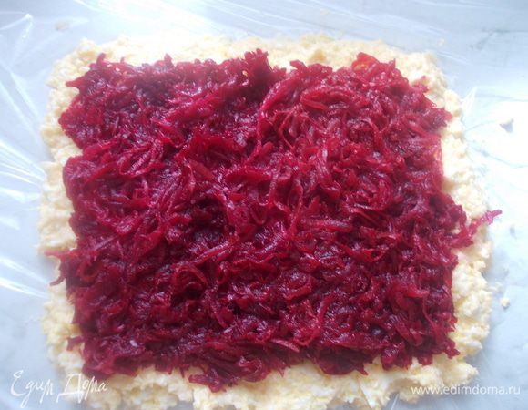 Затем потереть свеклу и отжать сок. Выложить сверху сыра и разровнять.