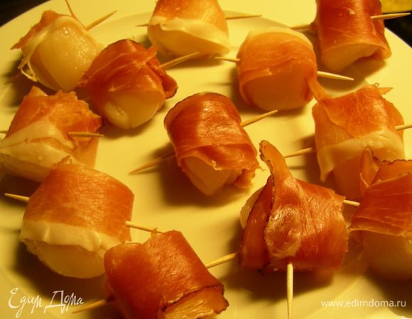 Гребешки моем и обсушиваем бумажным полотенцем. Оборачиваем их в бекон и прокалываем зубочисткой, чтобы хорошо держались. В сковороде разогреваем сливочное масло (1 ст.л.) и обжариваем гребешки по 2 минуты с каждой стороны. Бекон должен хорошо зазолотиться.
