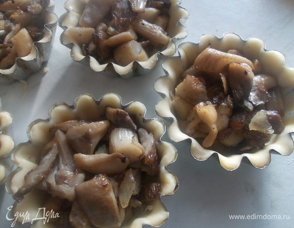 Затем в формочки положить обжаренные грибы. Немного их утрамбовать.