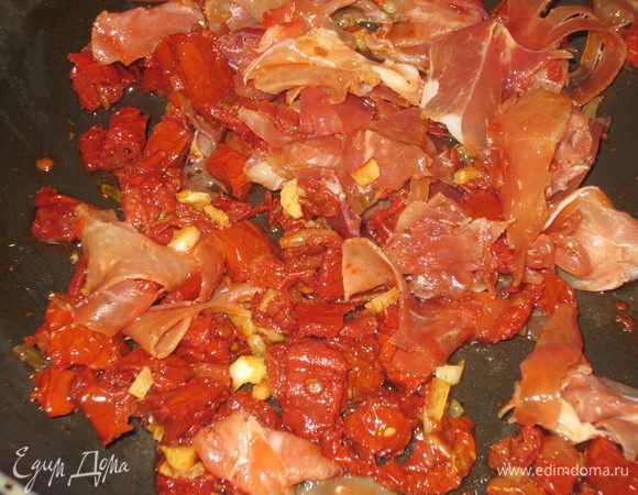 Чеснок измельчить, обжарить в оливковом масле  несколько минут.Добавить вяленые помидоры,  подкопченный окорок и готовить ещё 3 минуты.