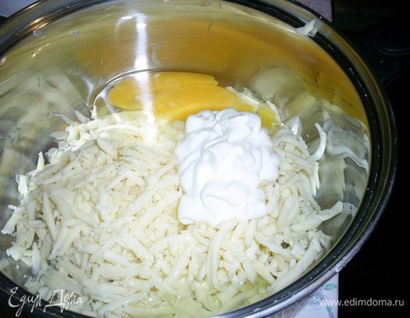 В отдельную емкость натираем сыр на крупной терке, добавляем сметану, яйцо и белок. Желток оставляем для смазывания верха пирога.
