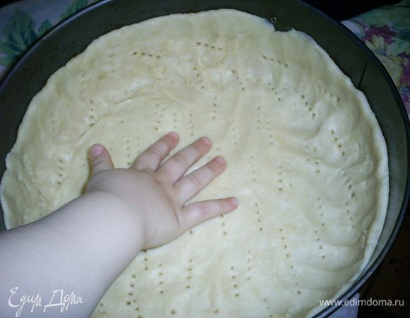 Достаем из холодильника тесто. Делим его на две неравные части. 2/3 теста пойдут на формирования дна и стенок и 1/3 оставляем для верха пирога. Большую часть теста руками распределяем по форме для выпекания. У меня круглая диаметром 23 см. Дно формы я выстилаю бумагой, чтоб пирог было легче вынять, бока ничем не смазываю. Не забываем про бортики, лучше их сделать повыше. Часто накалываем тесто вилкой.