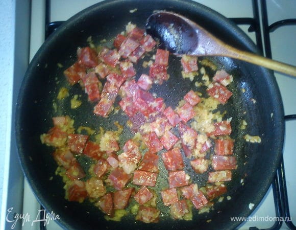 Обжарить чоризо с луком и чесноком на оливковом масле. Желательно это делать в той сковороде, которую можно будет поставить в духовку.