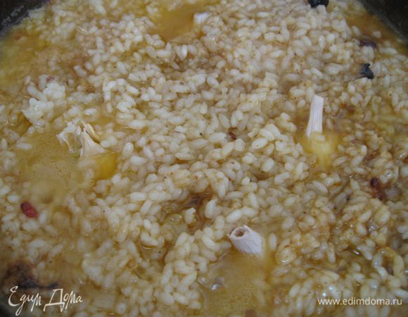 Через 10-15 минут, когда вода с поверхности риса почти выкипит, сделать лунки и «посадить» чеснок. Закрыть  крышкой, сделать  маленький огонь на 5 минут. Выключить  газ.