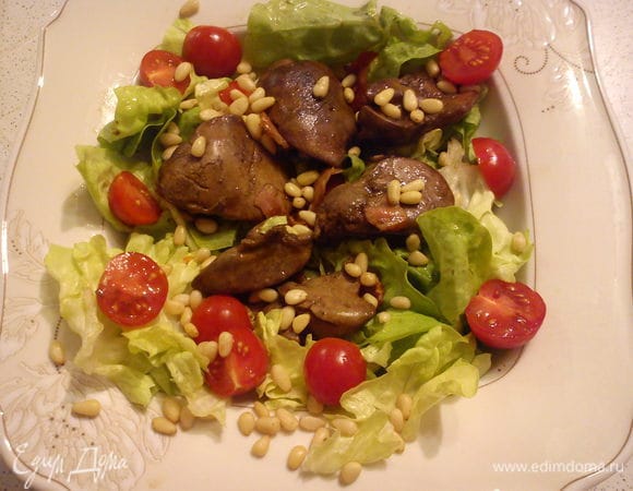 Листья салата порвать руками и выложить на тарелку. На листья выложить печень с беконом, помидоры и полить соусом из сковороды. Посыпать орешками. Подавать на стол желательно сразу.