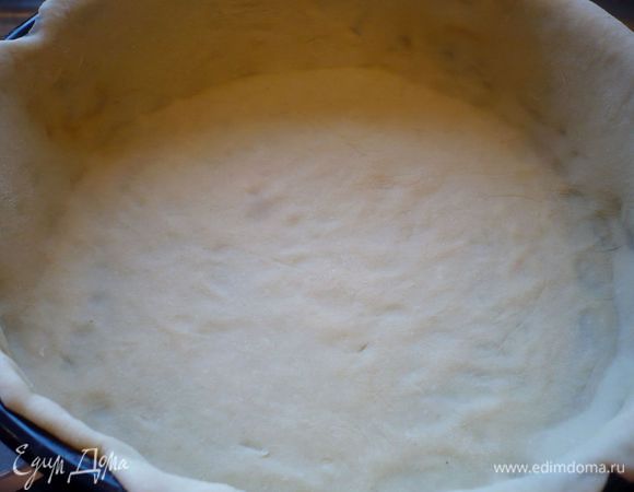  Духовку разогреваем до 200 градусов. Тесто делим на две части и раскатываем каждую на присыпанной мукой поверхности достаточно тонко. Выкладываем в смазанную маслом форму одну часть, образуя высокие бортики. 