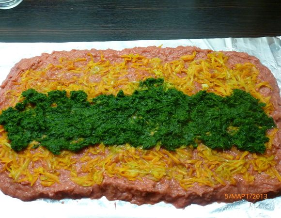 Фольгу смазать растительным маслом и выложить фарш толщиной примерно 2 см. Далее на фарш выложить обжаренные лук и морковь, следующий слой - шпинат.