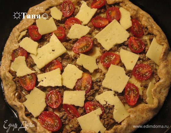 На тесто ложим кусочки сыра или натираем сыр на тёрку (У меня был сыр  нарезанный тонкими пластинки поэтому я его не могла натереть и поломала на кусочки,  в духовке он расплавился), посыпаем пармезаном, выкладываем слой говяжьего фарша, обжаренного с луком и часноком и любимыми специями, выкладываем снова сыр, раскладываем половинки помидорок черри, посыпаем пармезаном. 