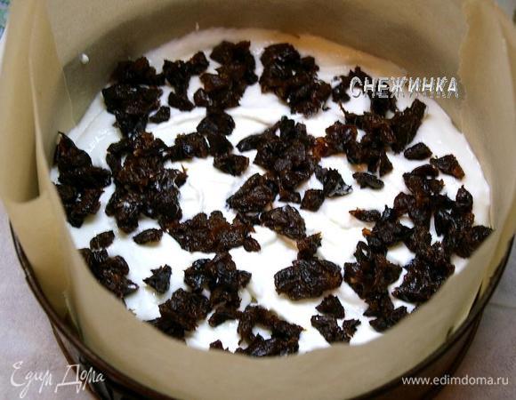 В разъёмную форму, в которой выпекался бисквит, вставляем кольцо из пекарской бумаги. На дно кладём один корж. Сверху выкладываем половину суфле. Распределяем промытый и измельчённый на кубики чернослив.