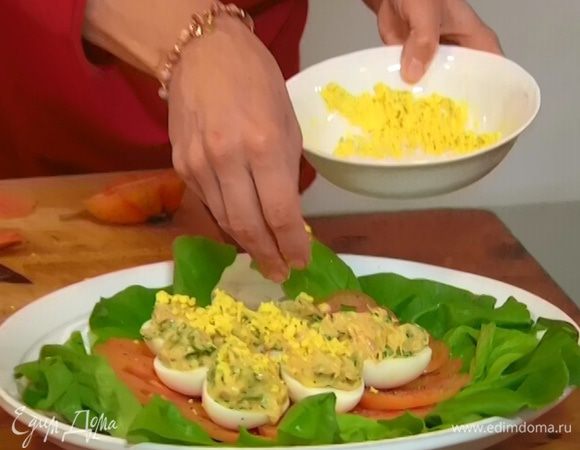 Оставшийся желток раскрошить и посыпать сверху фаршированные яйца.