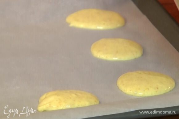 Противень выстелить бумагой для выпечки и ложкой выложить тесто в форме лепешек.