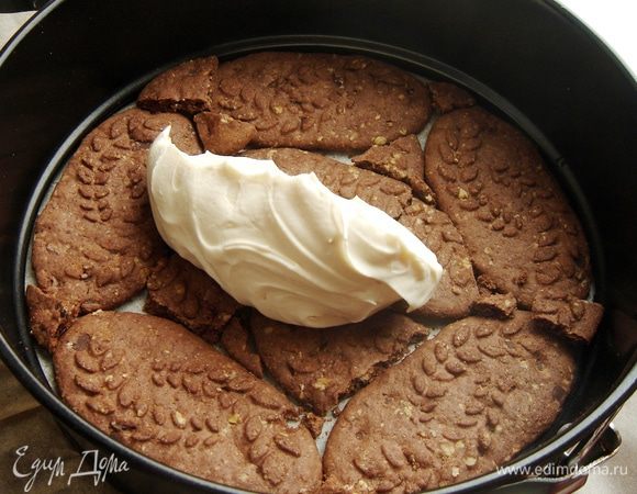 Дно разъемной формы выстелить пергаментом или пищевой пленкой. На дно формы выложить слой печенья, закрывая все пустоты. На печенье выложить 1 часть крема и разровнять его по поверхности печенья.