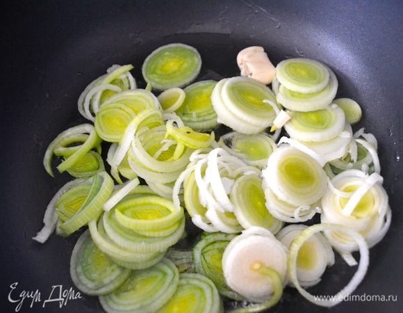 В большой сковороде разогреем оливковое масло и добавим обжариваться лук вместе с раздавленным зубчиком чеснока