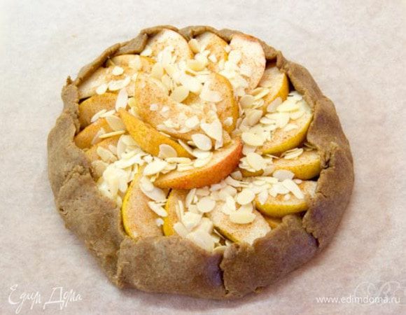 Прямо на пергаменте раскатываем тесто диаметром около 25 см.
Посыпаем центр 1 ст.л. сахара, выкладываем груши, снова посыпаем сахаром, корицей и орехами.
Края загибаем вовнутрь.