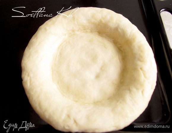 Затем каждую часть теста приплюснуть в центре и с помощью кулака выдавить серединку, чтобы она стала плоской, в то время как края лепешки должны оставаться толстыми. Нужно помогать себе костяшками указательных пальцев.