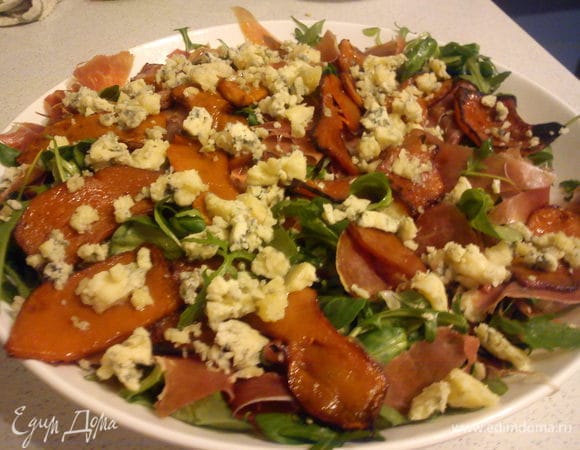 Добавить к листьям нарезанные помидоры, порвать руками хамон и перемешать. Сверху выложить тыкву и покрошить на нее сыр. 