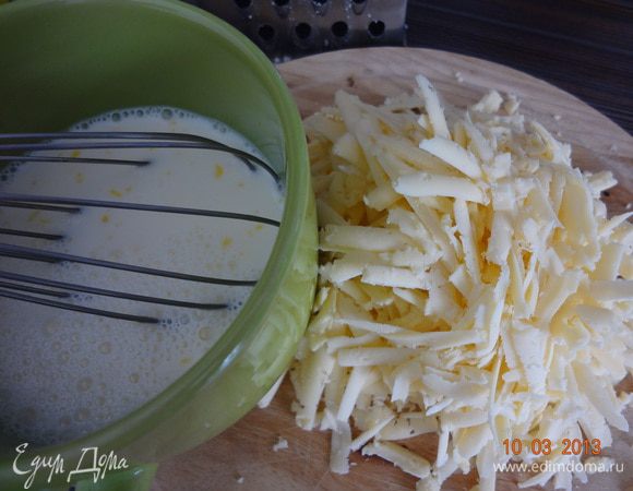 Готовим заливку. Молоко взбиваем с яйцами, еще я добавила сливки и мускатный орех, а соль по вкусу. Все перемешиваем хорошенько. Натираем сыр на крупной терке.