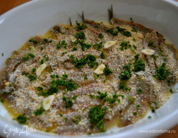 Сверху первый слой рыбы присыпаем немного сухарями и мелко рубленной петрушкой. Кладем несколько кружочков чеснока. Солим и перчим по вкусу. 