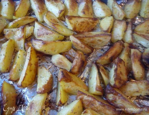 Лист застелить фольгой, смазать ее маслом. Выложить картофель в один слой. Запечь в духовке при 220 С почти до готовности.