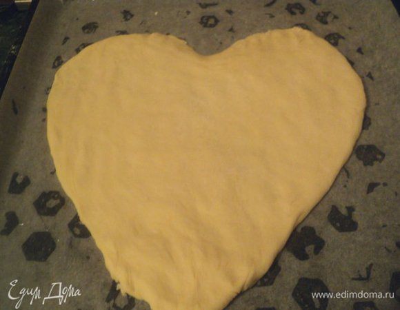 Дрожжевое тесто разделить на две части, одну часть немного меньше другой. Меньшую часть теста раскатать в пласт толщиной 1 см и вырезать сердце. Выложить на противень, смазанный маслом.