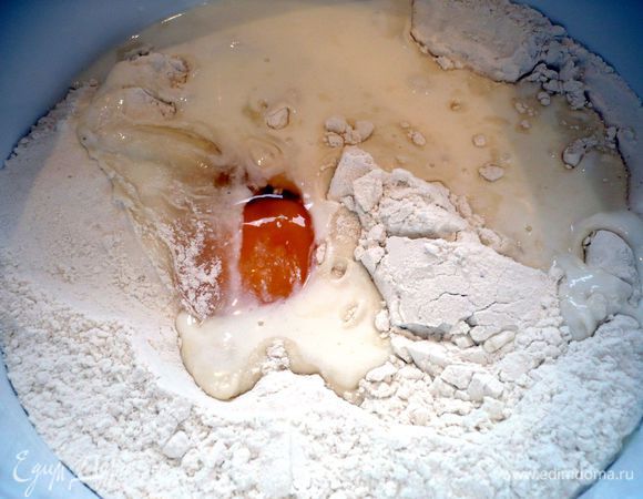 Готовим тесто. Делаем углубление в подсоленной муке и вливаем кефир, добавляем яйцо. Вымешиваем эластичное тесто.