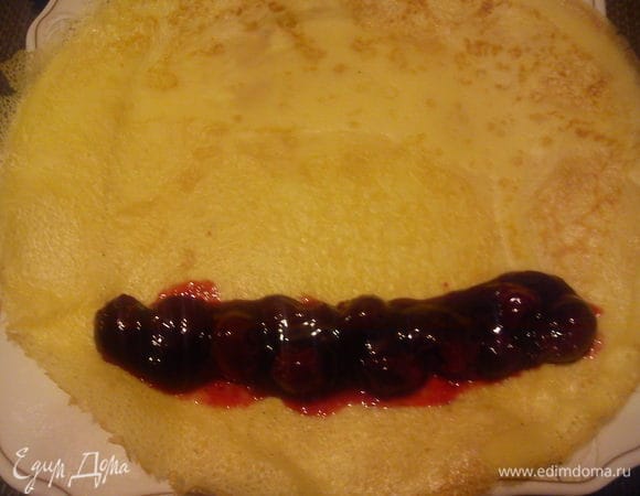 На другой блинчик выложить вишню и слегка скрутить в трубочку