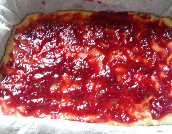 Достаем его из духовки. Наносим на него слой малинового варенья. 

