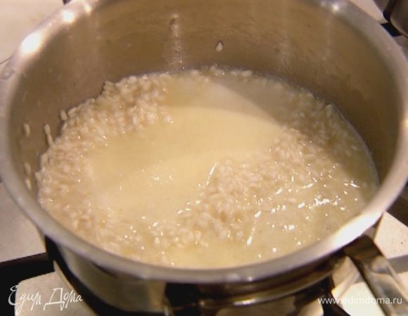 Когда рис станет прозрачным, убавить огонь и вливать небольшими порциями сладкое молоко, давая ему полностью впитаться в рис. Готовить 12–15 минут, почти до готовности риса.