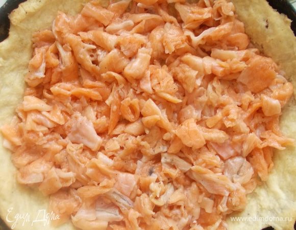 Тем временем порезать семгу и плавленный сыр, посолить, поперчить и добавить немного орегано.. Когда тесто пропечется, вынуть его и уложить начинку.