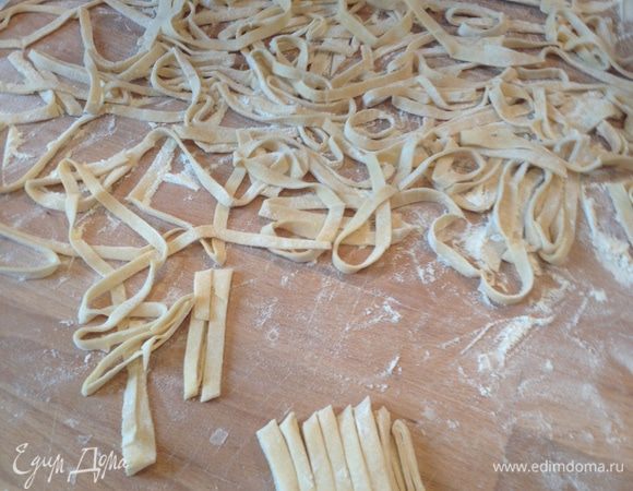 Пока варится бульон, приготовим лапшу:
Все ингредиенты для лапши смешать, замесить крутое тесто, завернуть его в пищевую пленку, дать полежать 10 минут.
После раскатать тонкое тесто (до 1 мм), обсыпать мукой, чтоб не слиплось, свернуть рулетом и нарезать узенькими полосками. Рассыпать лапшу и дать ей просушиться, пока варится бульон.
