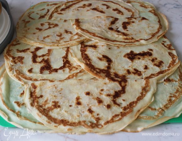 Начинаем собирать рулет. Освободите заранее ровное место в морозильной камере (если нет, то верхнюю полку в холодильнике). На широкую разделочную доску застелить пищевую пленку. Выложить на нее блины так, чтобы жду ними не было просвета (внахлест)...красивой стороной вниз