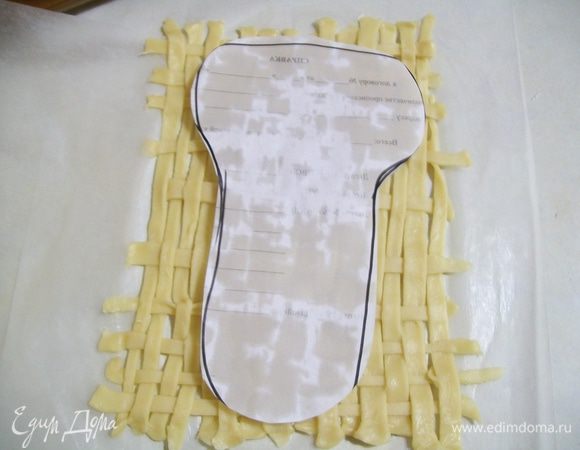 На бумаге сделать выкройку лаптей, вырезать ее, приложить на переплетенный  коврик- тесто . 

Прикладывать не вдоль, а поперек. 

Таким образом на одном пергаменте- у меня получилось два больших лаптя и один маленький. 

Приложить выкройку на тесто и аккуратно обвести ножом - вырезая.  
 
Ножницами разрезать пергмент  на 3 лаптя - части , каждый  по  отдельности . 