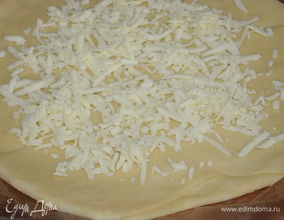 переложить на противень, застеленный ковриком для выпечки. Немного наколоть вилкой. Присыпать 50 г сыра