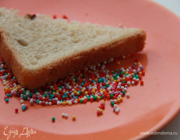 Намажьте хлеб сливочным маслом и разрежьте по диагонали. 
Обмакните смазанной стороной в тарелку с конфетти.