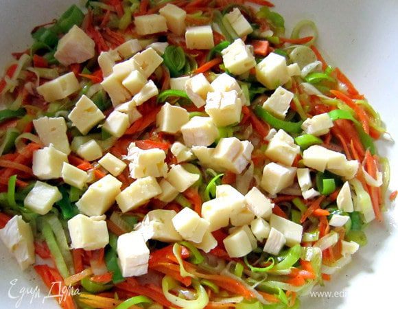 Сыр нарезать небольшими кубиками. Половину сыра добавить в сотейник к овощам. Посолить, поперчить по вкусу и перемешать.