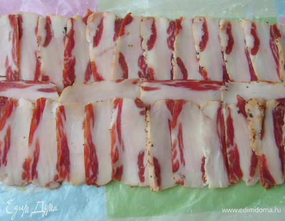 Порезать сырокопченый бекон тонкими ломтиками. Выложить их внахлест на пищевую пленку.