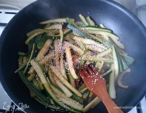 Разогреть в сковороде кунжутное масло и обжарить цукини очень быстро (3-4 минуты). Все время помешивать. Влить соевый соус и посыпать кунжутом. Прогреть 2 минуты.